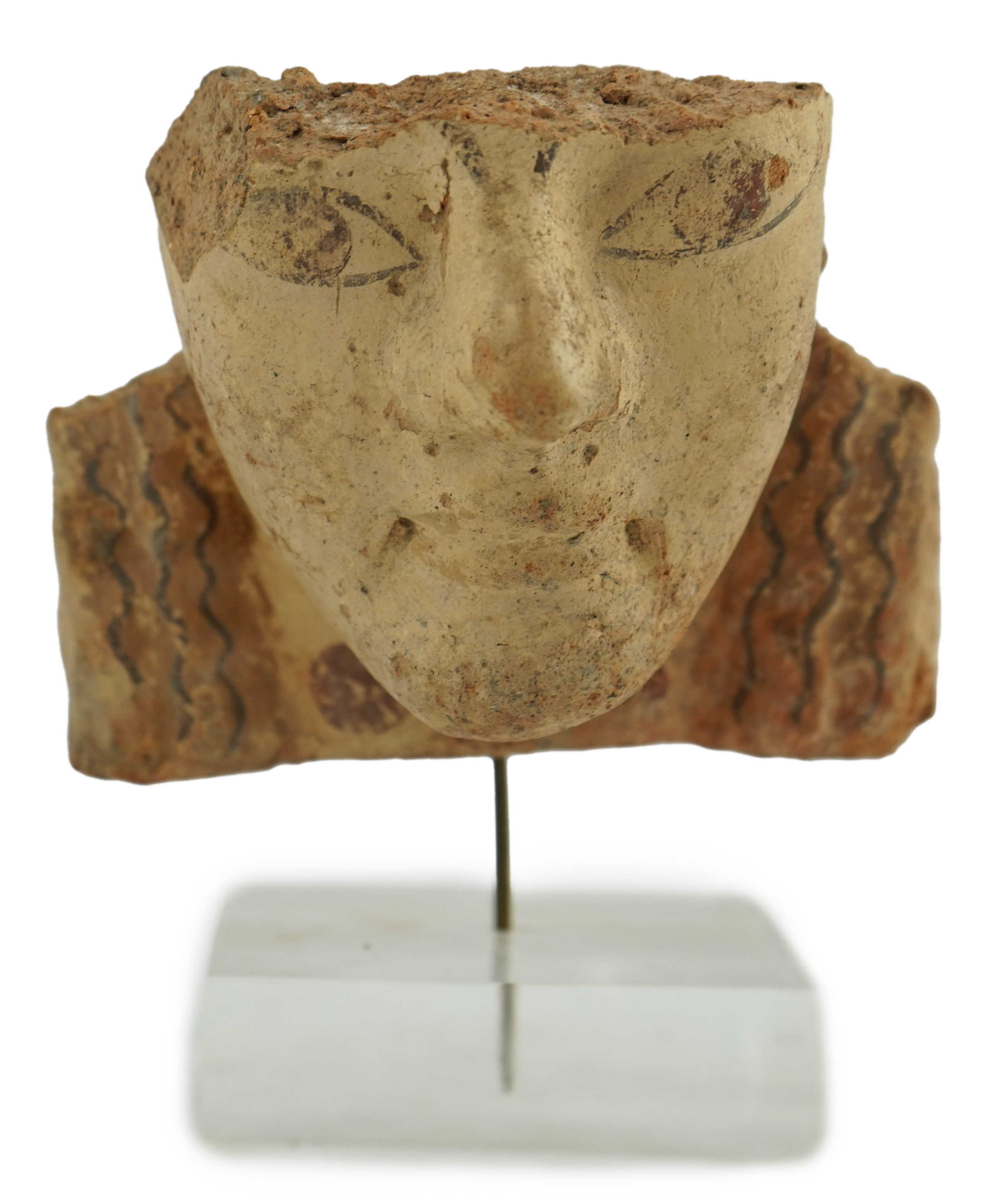 An Etruscan terracotta antefix, modelled as a head with polychrome painted features, 6th-5th century BC.